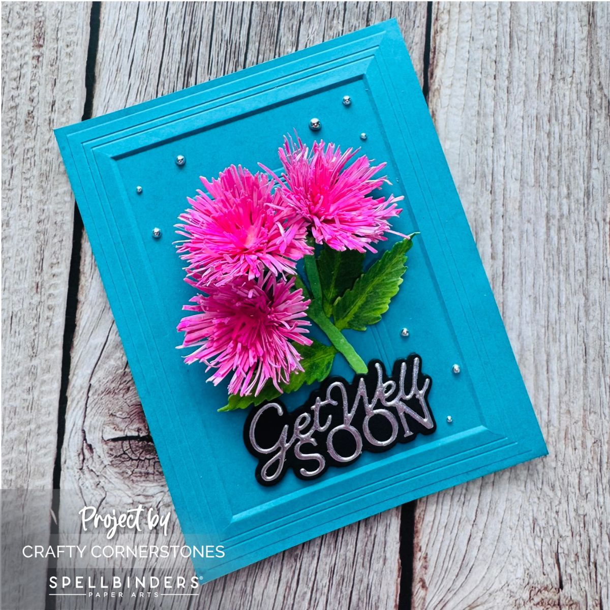 Handmade turquoise Get Well Soon card featuring pink tassel flowers, green leaves, and silver embellishments by Crafty Cornerstones.