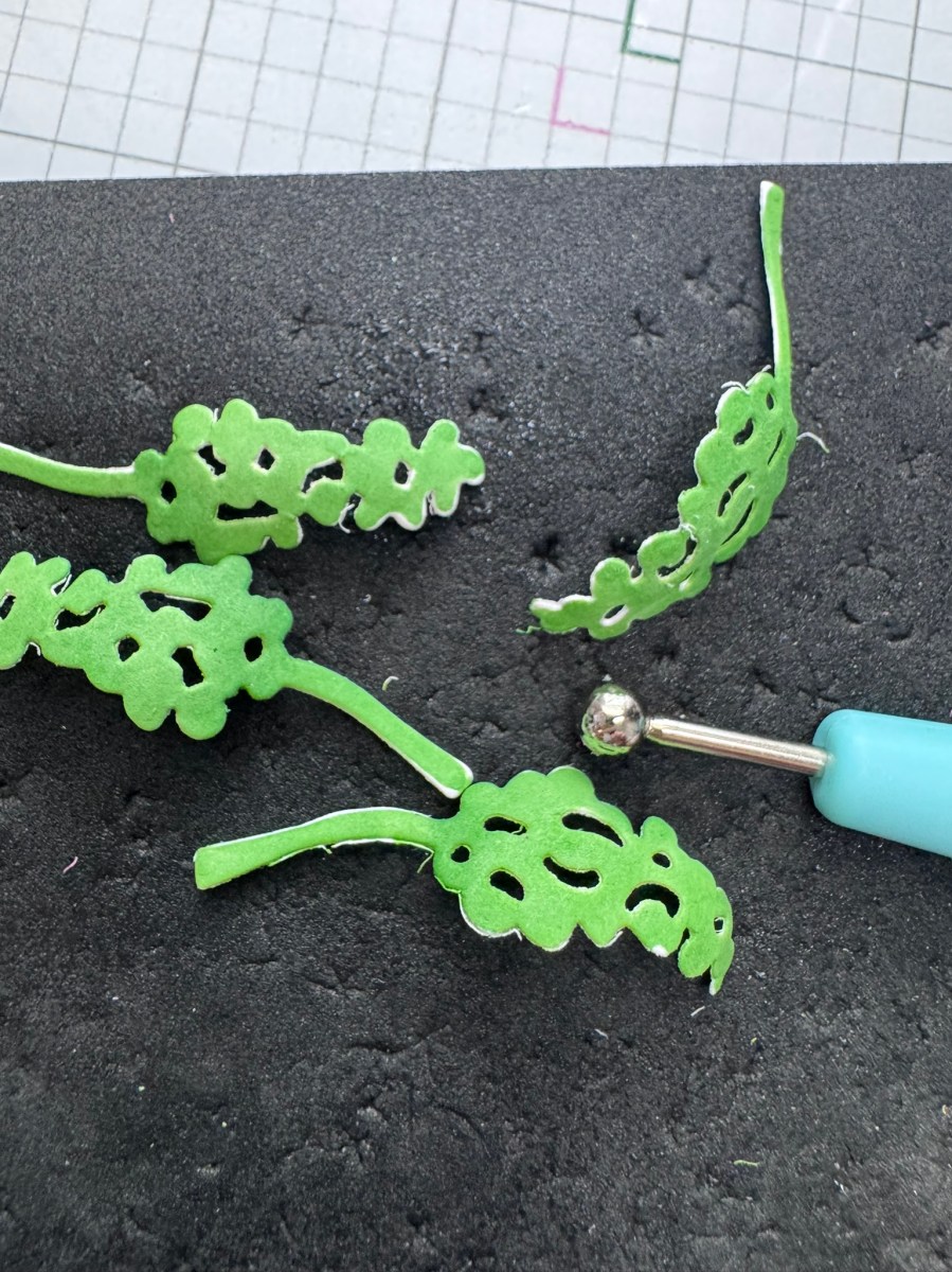 Green die‑cut leaves shaped with a ball stylus on a crafting mat, part of the Poetic Foliage Set process for dimensional cardmaking.